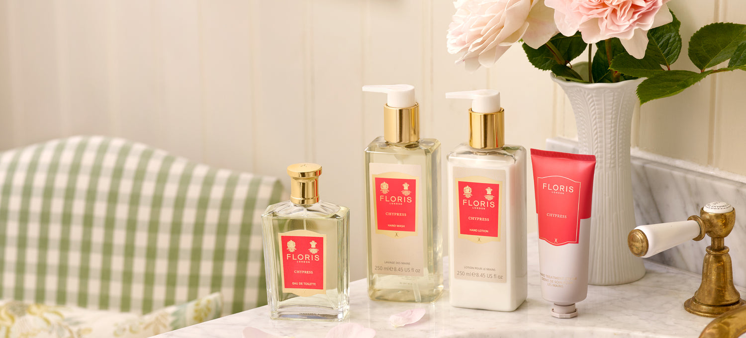 The Chypress collection on a marble sink beside a vase of roses and a green check Chesterfield chair.