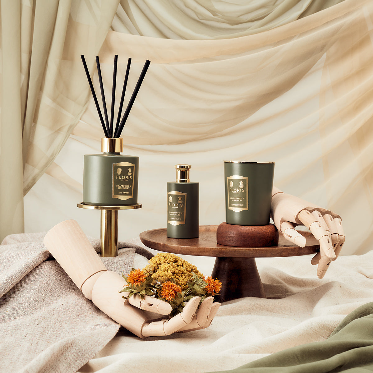 Floris London Grapefruit & Rosemary Reed Diffuser 200ml, displayed with wooden hands, flowers, and draped fabric in an elegant aromatherapy setting.