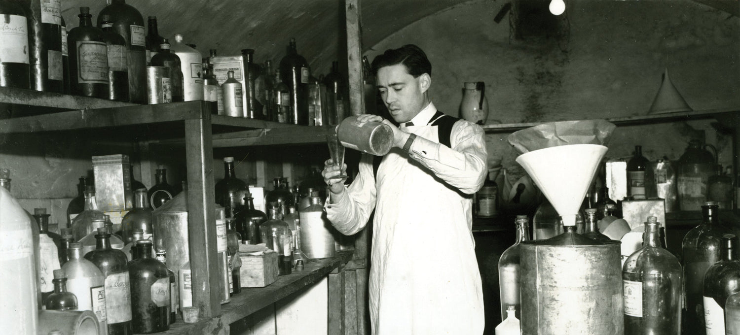 An older image of a Floris family member pouring oils into a bottle