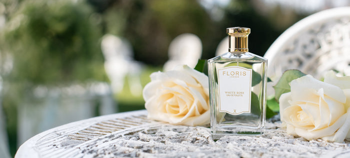 Bottle of White Rose Eau De Toilette on a white iron garden table.