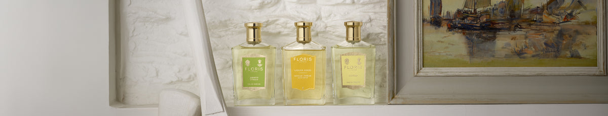 Three Floris perfume bottles in varying scents are displayed neatly on a shelf next to an abstract painting.