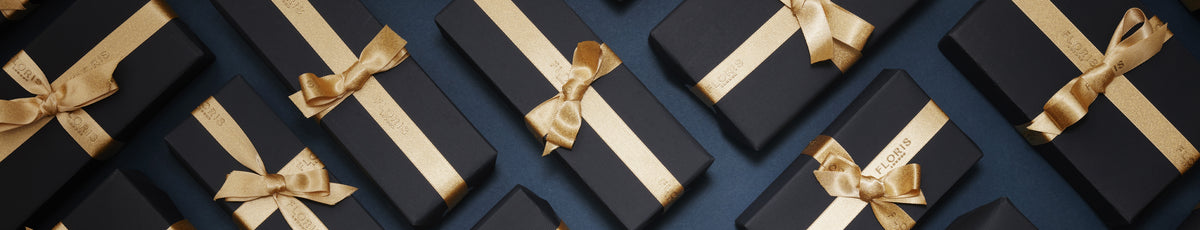 Many black gift boxes with gold ribbons arranged diagonally on a dark background.