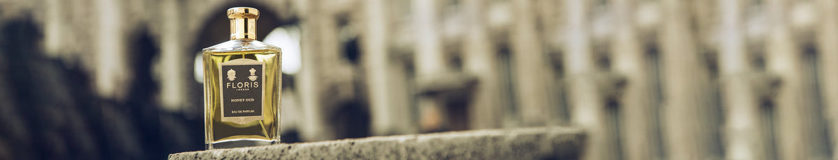 Perfume bottle labeled "Floris" on stone ledge, blurred architectural background.
