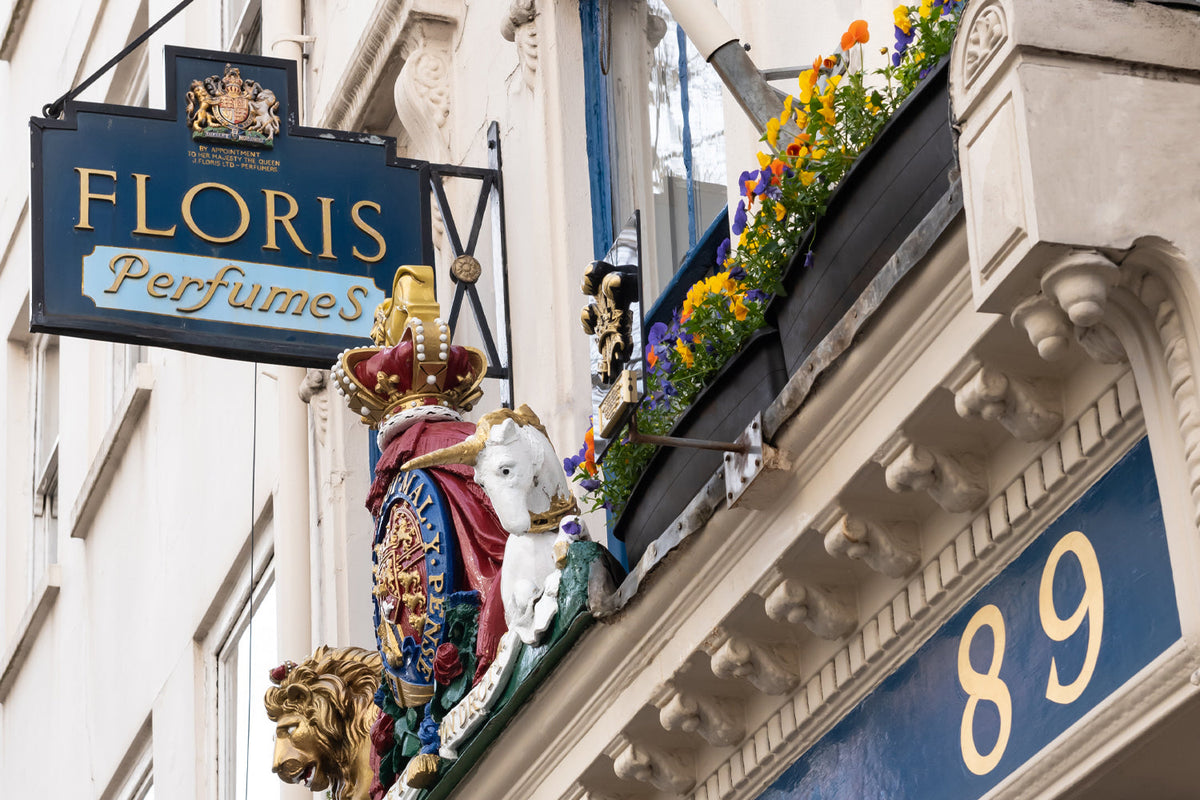 A storefront sign for Floris Perfumes at number 89, featuring a Royal Warrant crest, a unicorn and lion emblem, and a flower box on the ledge above.