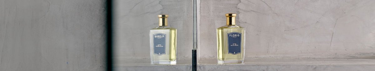 Perfume bottle and wooden soap dish on a rustic bench with a green plant in the corner.