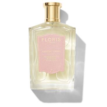 A clear glass perfume bottle with a gold cap and a pink label beautifully showcases "Floris London," "Ledger Series," and "Malmaison Encore." This floral oriental fragrance exudes a captivating allure.