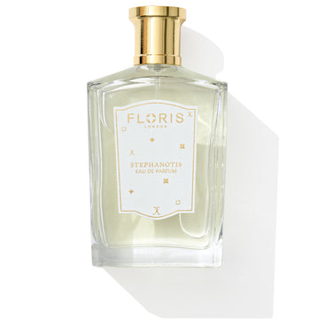 A transparent perfume bottle with a gold cap, labeled "Floris London UK Stephanotis - Eau de Parfum | Limited Edition," is displayed against a white background. This fragrance encapsulates the essence of stephanotis and orange blossom, enhancing its sophisticated design with a delicate touch.