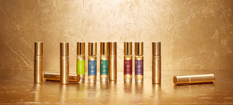 A collection of six perfume bottles with golden caps arranged on a gold surface with a gold backdrop.