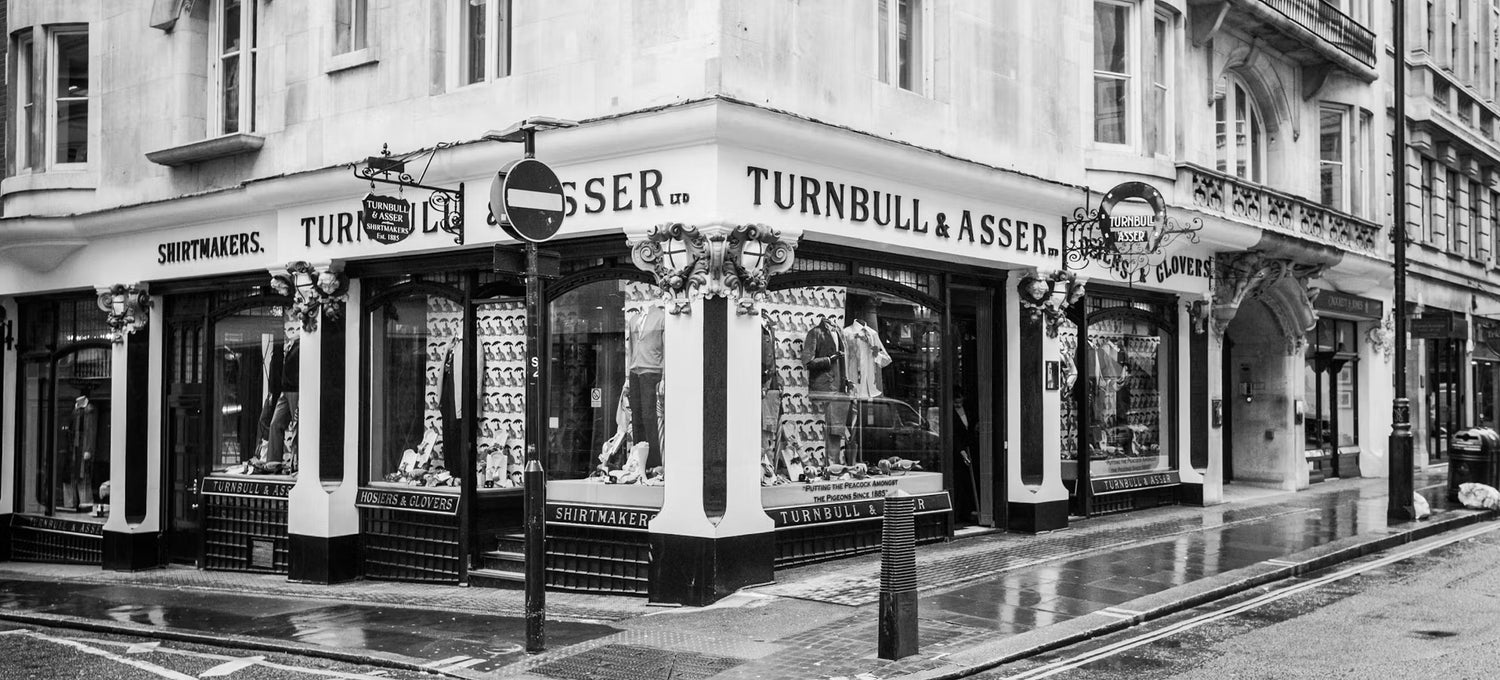 Black and white photo of the historic Turnbull & Asser store front, showcasing a classic street scene with vintage charm.