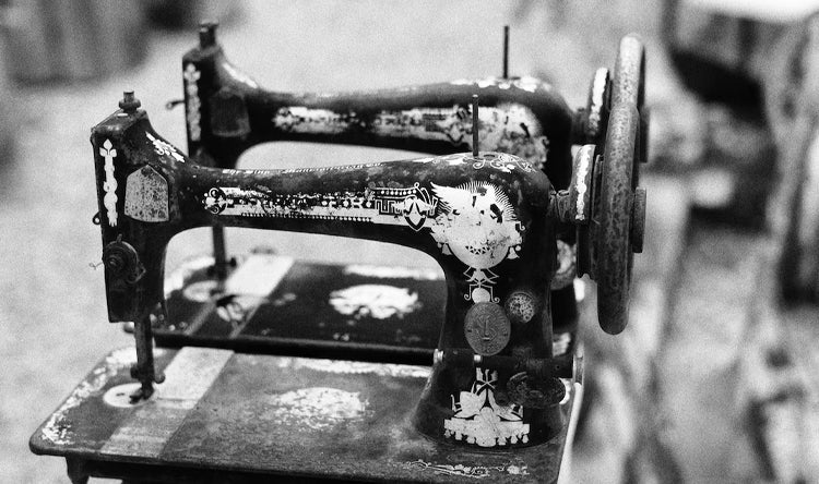 Close-up of an antique sewing machine with a worn, industrial appearance, highlighting the craftsmanship and history of the tool.