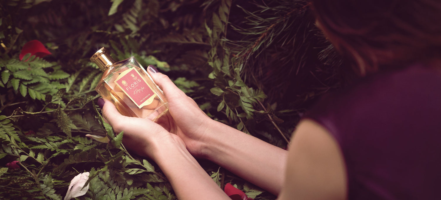 A lady holding a bottle of A Rose For... Eau de Parfum by a tree