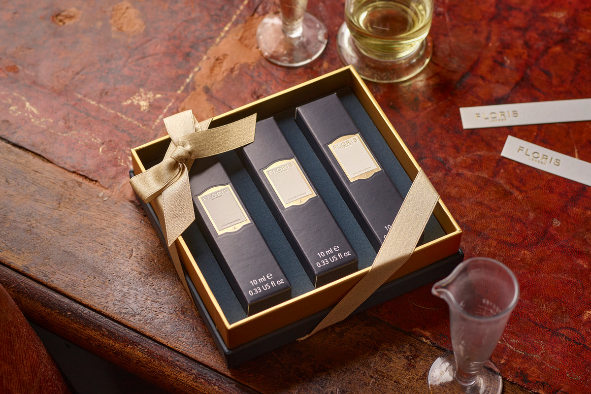 Three slim bespoke Fragrance - Customisation Replenishment 3 x 10ml Trilogy perfume bottles presented in a gift box tied with a gold ribbon.