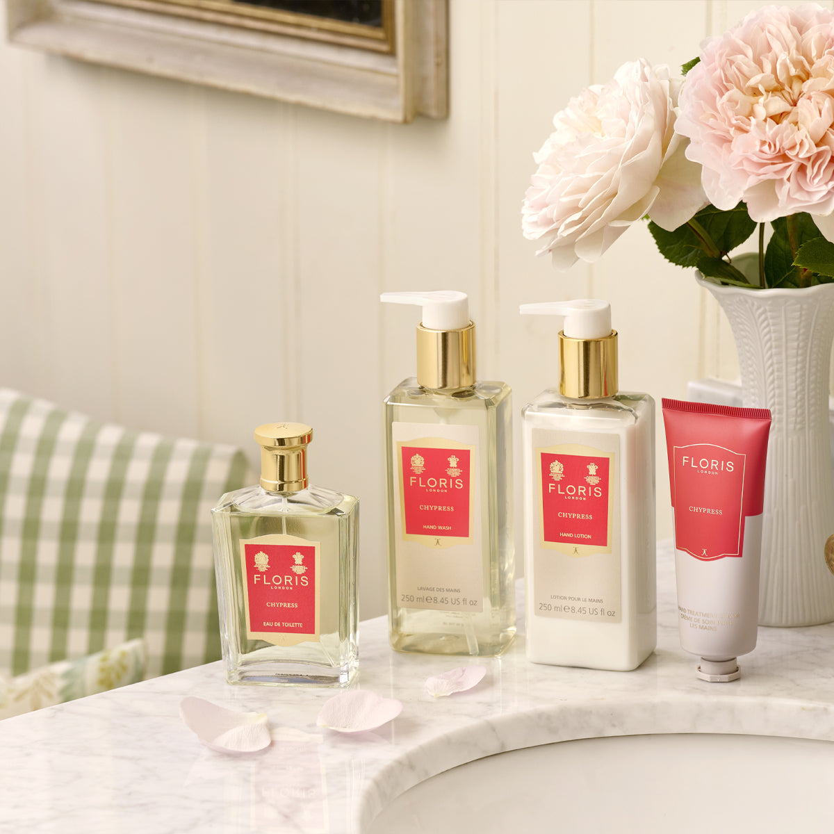 Floris London's Chypress Eau de Toilette set on marble with orange flowers and petals, against a white paneled backdrop.