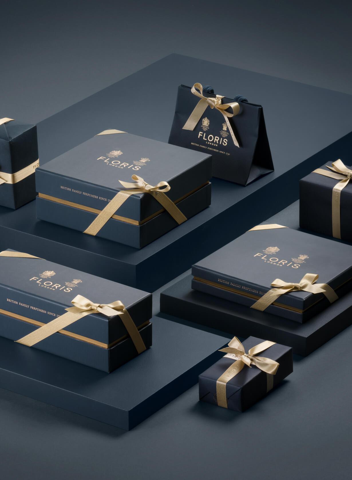 Dark blue gift boxes with beige ribbons, branded "Floris," displayed on dark stacked platforms.