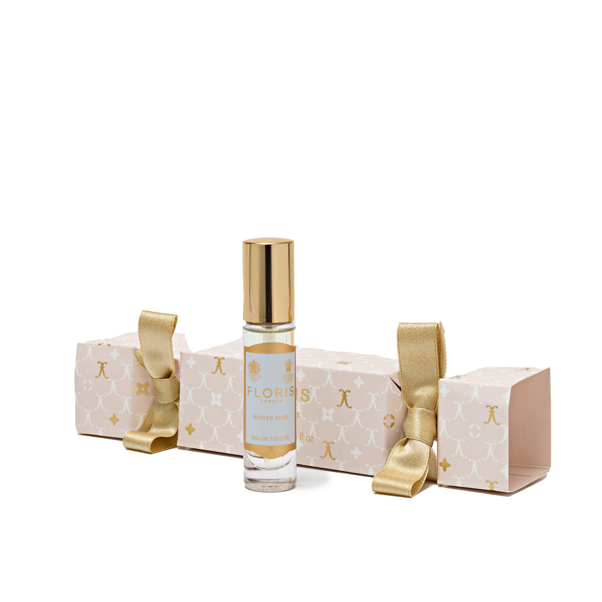 The White Rose Holiday Cracker by Floris London, with its gold ribbon on both ends, is placed next to a perfume bottle featuring a gold cap, beautifully capturing the essence of a cherished British tradition.