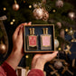 Hands holding the exquisite Cherry Blossom Duo from Floris London, its delicate fragrance perfectly complementing the festive intensity of a beautifully decorated Christmas tree.