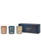Three beautiful candles from the Floris London Miniature Candle Collection in brown, teal, and ivory rest elegantly beside a blue and gold packaging box.