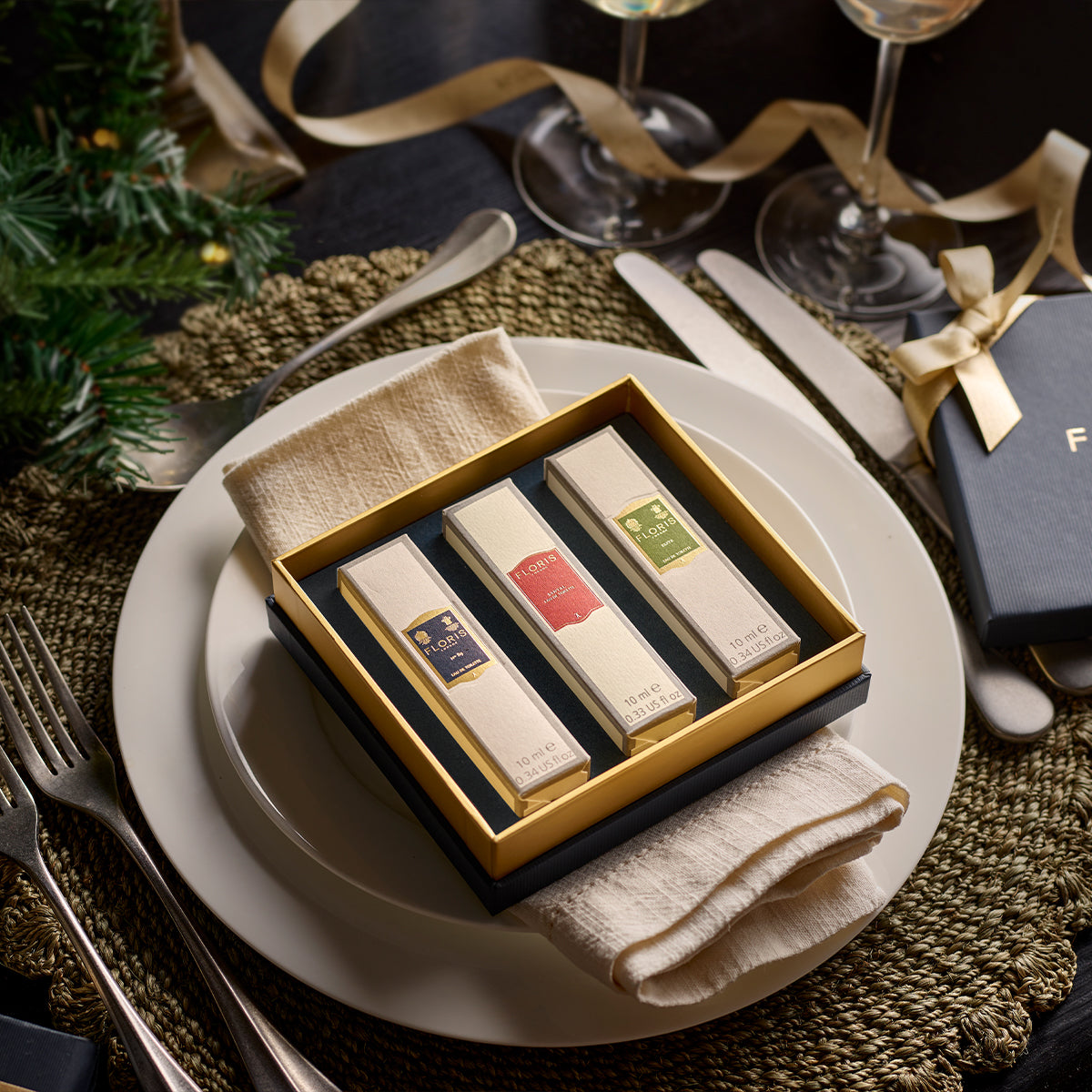 An exquisite gift set featuring Perfumer's Trilogy: For Him by Floris London, elegantly presented on a festive dining plate, surrounded by silverware and holiday decor, capturing the spirit of the festive season.