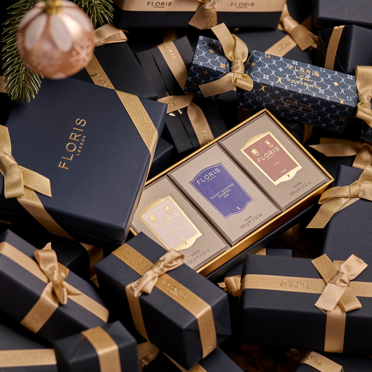 A boxed Soap Collection For Her from Floris London, featuring three exquisite soap products, nestled in-between beautifully gift wrapped presents. This luxurious gift set is perfect for the holiday season.