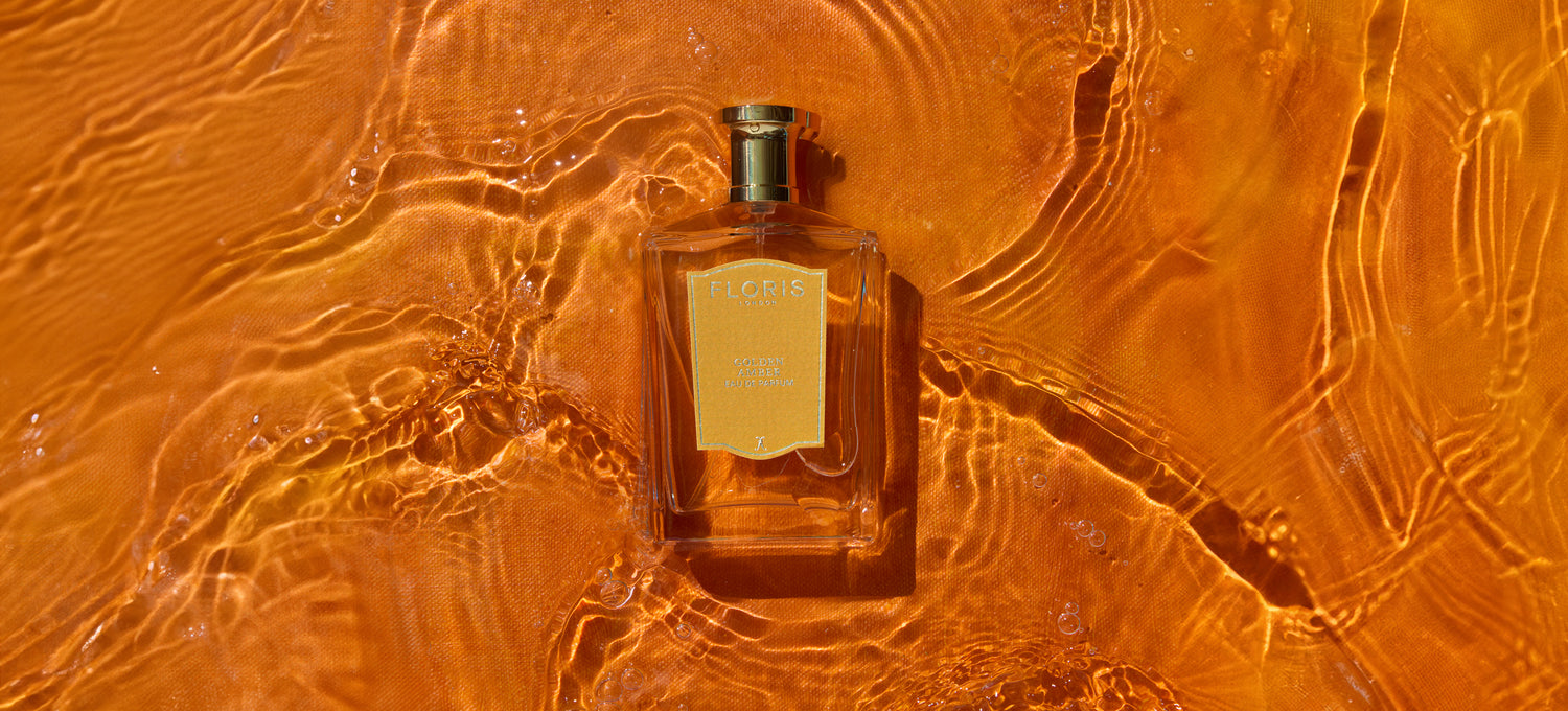 A bottle of Floris perfume floats on water with an orange hue, highlighted by sunlight reflections.