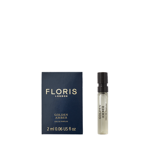 A 2 ml sample vial of Floris London Golden Amber - Eau de Parfum beside its blue and gold box. A refined vegan scent experience.