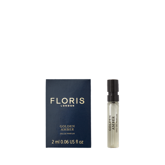 A 2 ml sample vial of Floris London Golden Amber - Eau de Parfum beside its blue and gold box. A refined vegan scent experience.