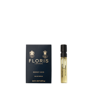 A Floris London Honey Oud - Eau de Parfum sample vial stands beside its navy blue and gold box, evoking the warmth of English honey and oud.