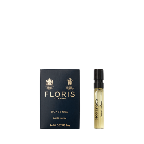 A Floris London Honey Oud - Eau de Parfum sample vial stands beside its navy blue and gold box, evoking the warmth of English honey and oud.