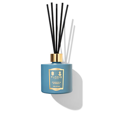A Hyacinth & Bluebell reed diffuser by Floris London, featuring black reeds and a gold label, exudes a floral fragrance of spring flowers against a white background.