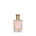 A transparent perfume bottle with a gold cap and pink label reads "Floris London Lily - Bath Essence," offering a delicate lily of the valley floral scent.