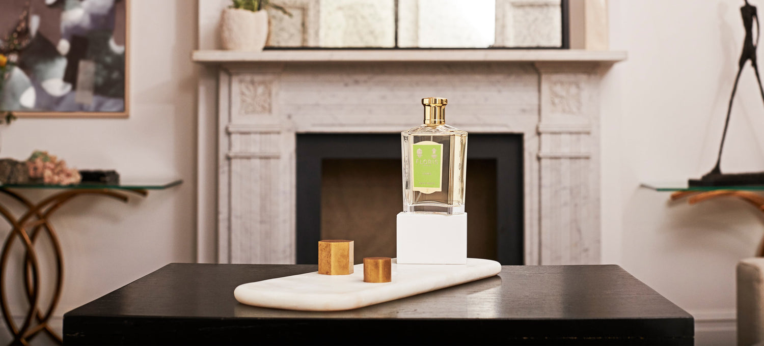 A perfume bottle on display in a modern living room with a marble fireplace and minimalist decor in the background.