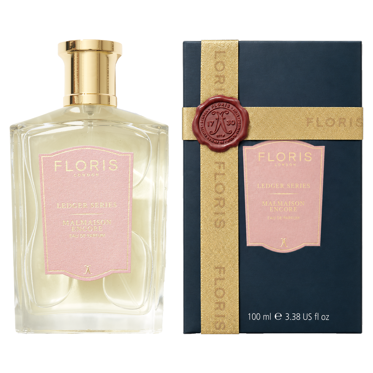 A Floris London UK Malmaison Encore fragrance bottle and its dark blue box, both featuring pink labels with gold lettering and a wax seal on the box ribbon.