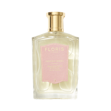 Clear glass bottle of Floris London Malmaison Encore perfume with a gold cap and pale pink label, featuring floral oriental notes of cedarwood, musk, and patchouli.