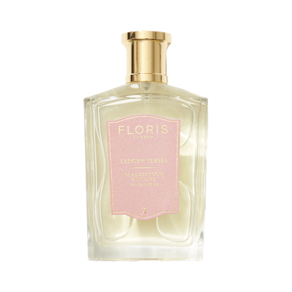 Clear perfume bottle with gold cap and pink label reading "Floris London UK, Malmaison Encore," exuding captivating allure.