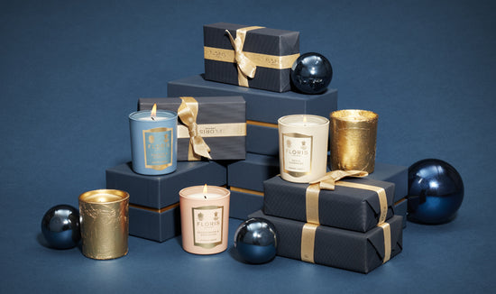 Three miniature candles displayed on a pile of wrapped gifts and blue Baulbauls. 