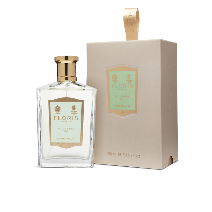 A bottle and box of "Mulberry Fig - Eau de Parfum (BF)" by Floris London, featuring gold and tan accents, are displayed on a white background. This perfume offers a captivating and elegant scent with a delightful blend of fig and cardamom for a nuanced floral amber fragrance.