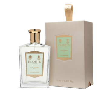 A bottle and box of "Mulberry Fig - Eau de Parfum (BF)" by Floris London, featuring gold and tan accents, are displayed on a white background. This perfume offers a captivating and elegant scent with a delightful blend of fig and cardamom for a nuanced floral amber fragrance.