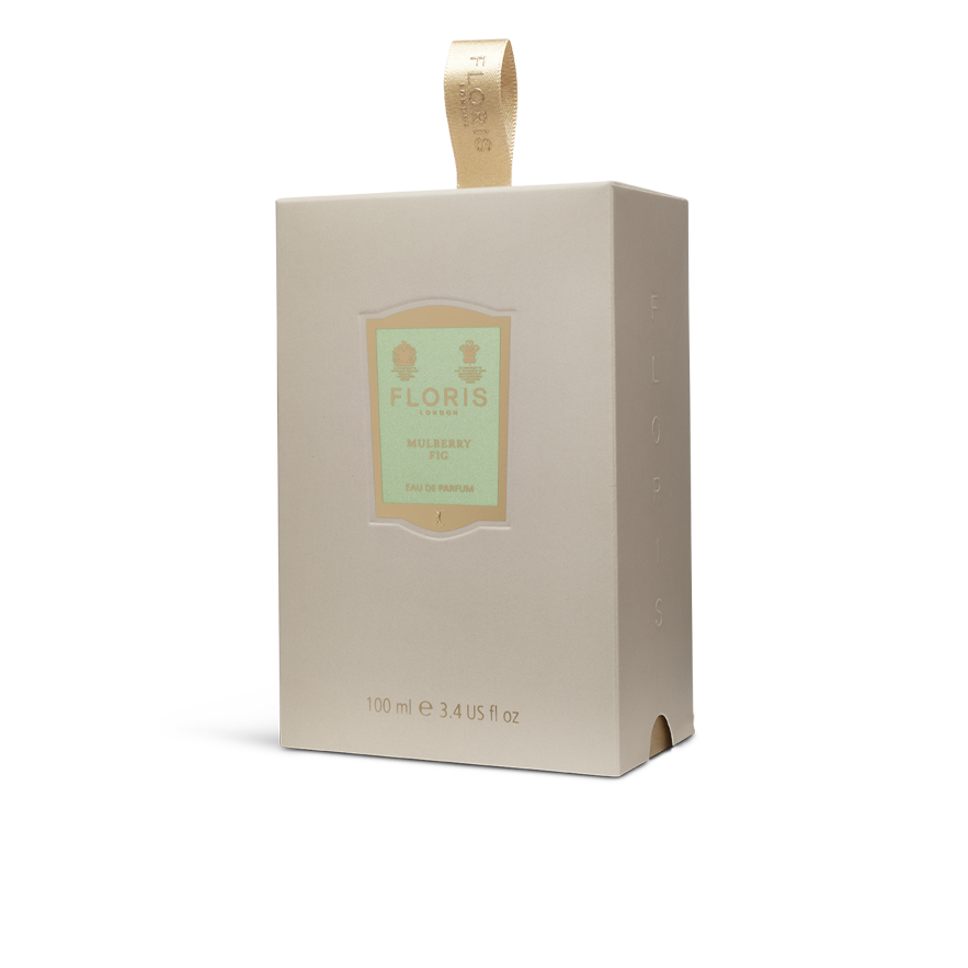 A beige perfume box labeled "Mulberry Fig - Eau de Parfum (BF)" by Floris London, adorned with a gold ribbon on top, captures the enchanting scent of fig and cardamom within its floral amber fragrance.