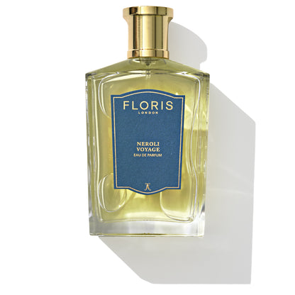 A bottle of Floris London's Neroli Voyage Eau de Parfum featuring a gold cap and a blue label, casting a shadow on a white background. This unisex fragrance boasts a refreshing blend of neroli and citrus marine notes.