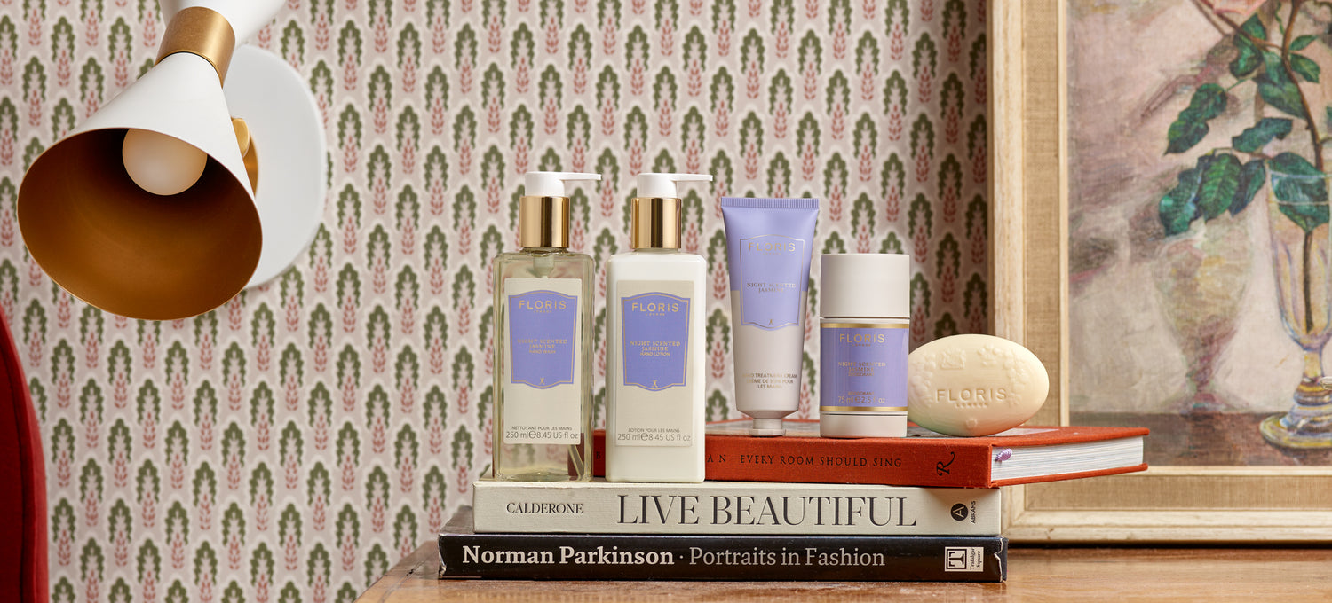 Night Scented Jasmine products by Floris London US, arranged on a mantelpiece alongside a vintage portrait, small potted plants, and delicate flowers, highlighting a refined and nostalgic aesthetic.