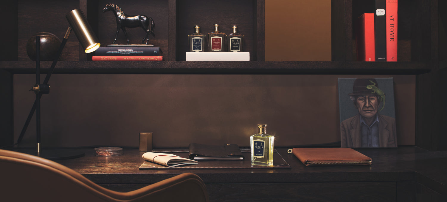 In a dark study, a bottle of No. 89 is spotlighted on a desk, with shelves above holding various other fragrances.