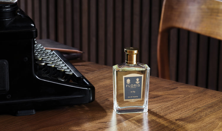 A bottle of No. 89 on a wooden desk next to an old-fashioned typewriter.