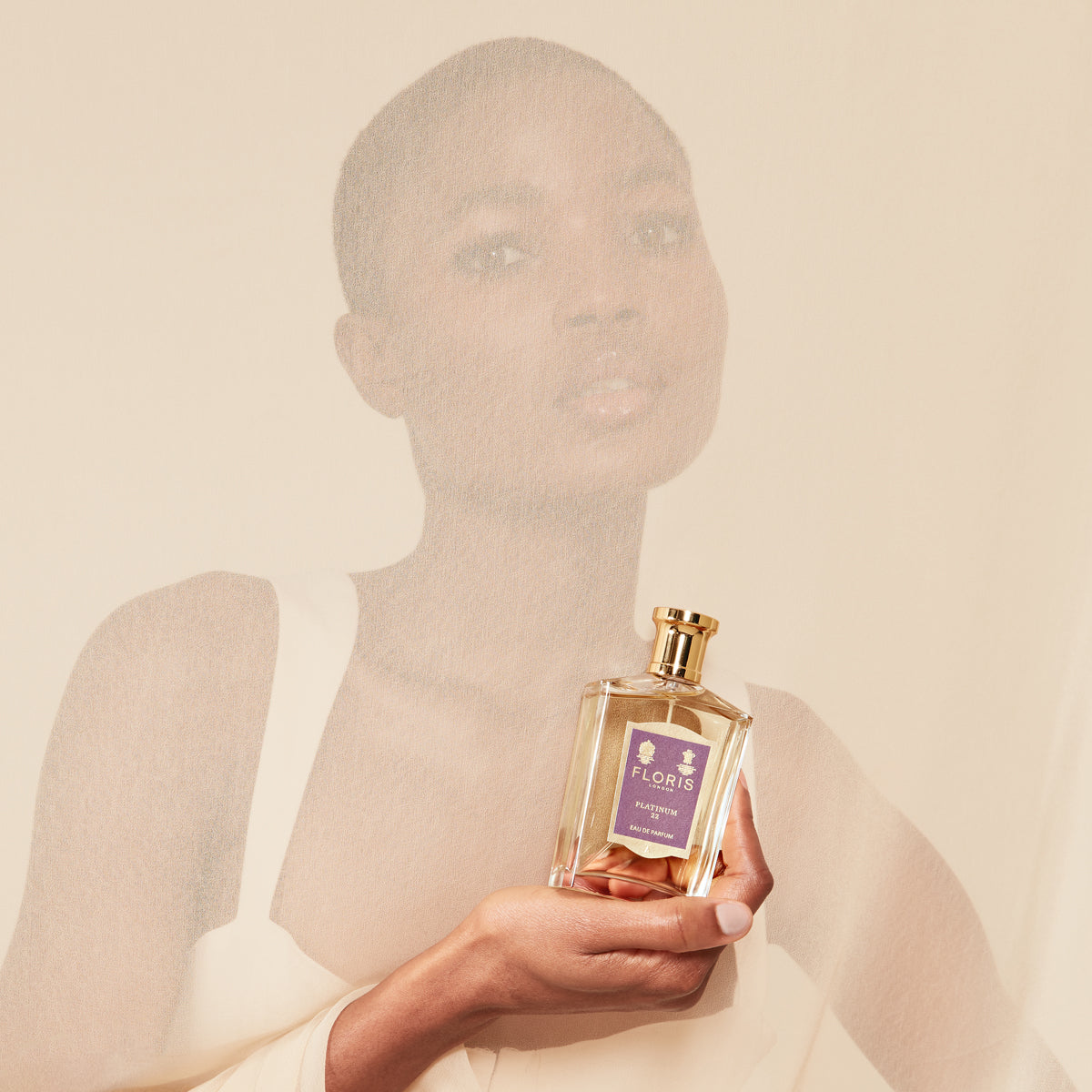 Person holding a Floris London Platinum 22 - Eau de Parfum bottle, with a soft-focus effect over their face and shoulders.