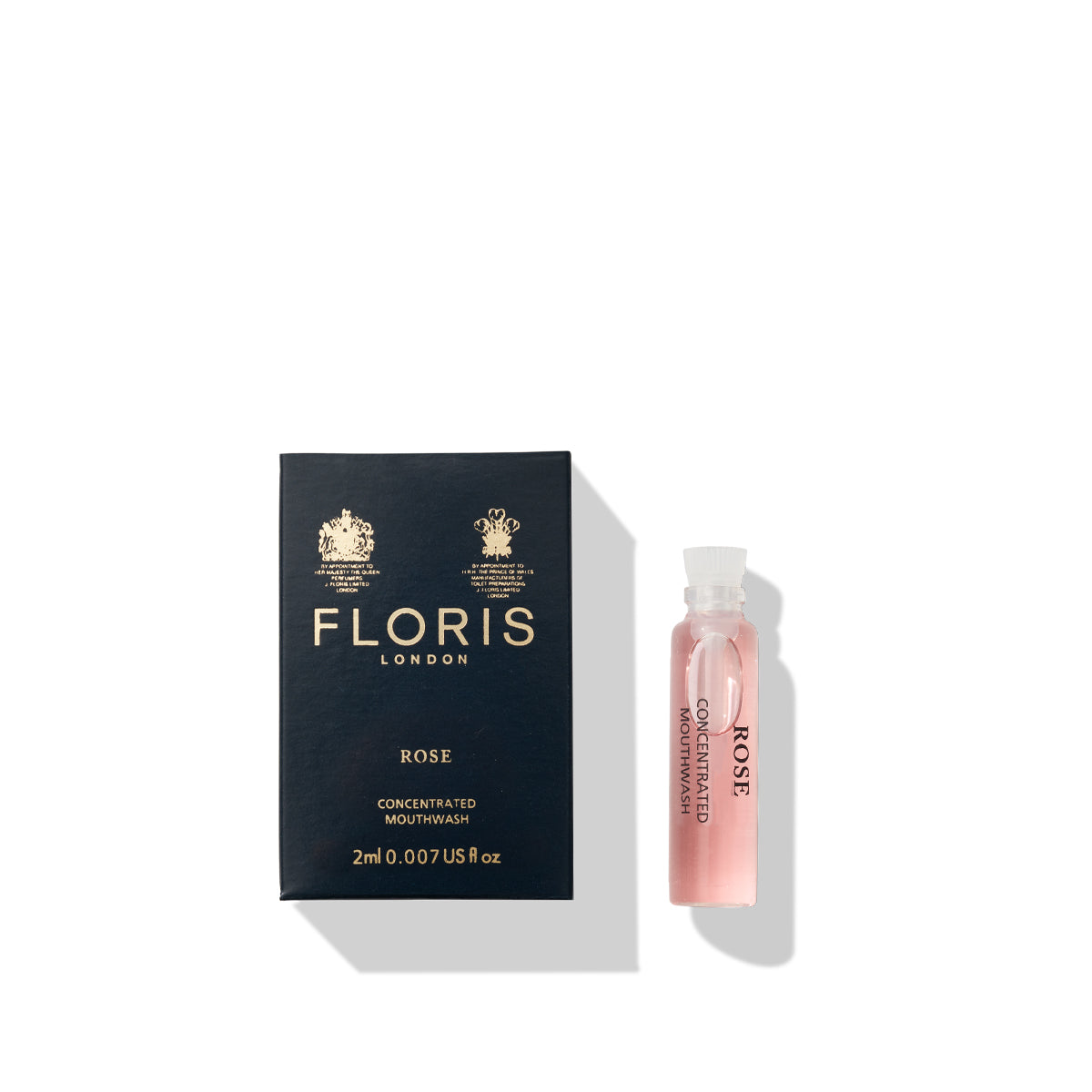 A small vial of Floris London Rose Mouthwash, celebrated for its pure rosewater and floral flavor, sits next to its black packaging on a white background.