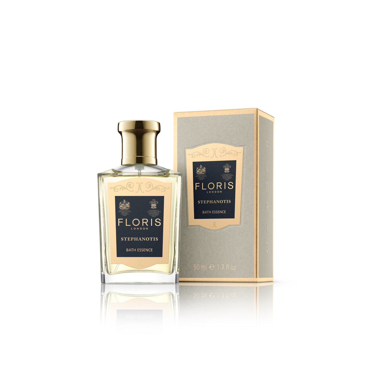 A bottle of Stephanotis Bath Essence by Floris London, with a floral scent, sits next to its elegant gold and navy detailed box.