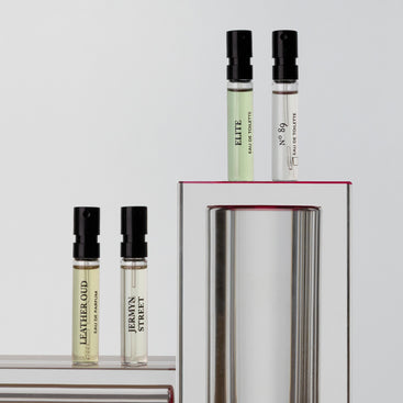 Four vials from Floris London's Pick Your Own - Sample Set, labeled Leather Oud, Herman Street, Elite, and No 89, displayed on reflective stands.