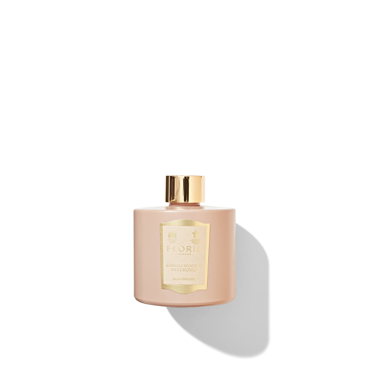 A pink bottle with a gold cap and a label of Floris London Sandalwood & Patchouli - Reed Diffuser against a white background, exuding an inviting woody amber aroma.