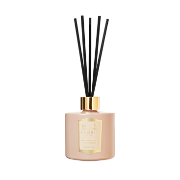 The Sandalwood & Patchouli Reed Diffuser by Floris London features a woody amber scent with rose and jasmine notes in a pink vessel with black sticks.