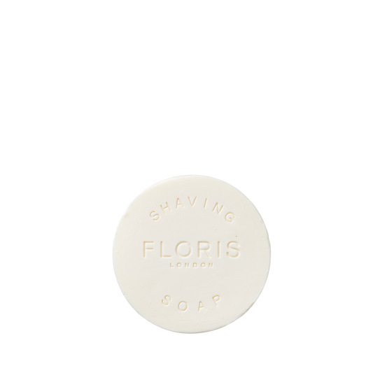 The Santal Shaving Soap Refill by Floris London is a round, white soap embossed with the logo, creating a creamy lather for a smooth, luxurious shave.