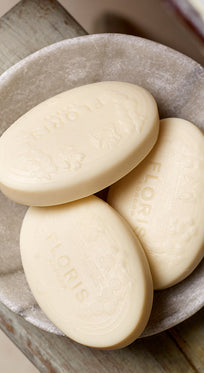 Three embossed soap bars with a nourishing vegetable base rest in a stone dish, showcasing the Floris London Soap Collection: Pick Your Own.